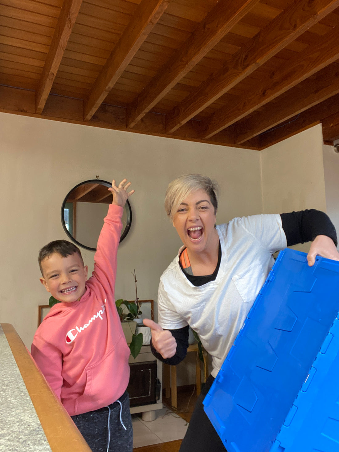 Rebekah Holmes and her son Otis celebrate the launch of Clutter Collect. They are smiling and Rebekah is holding a blue Clutter Box